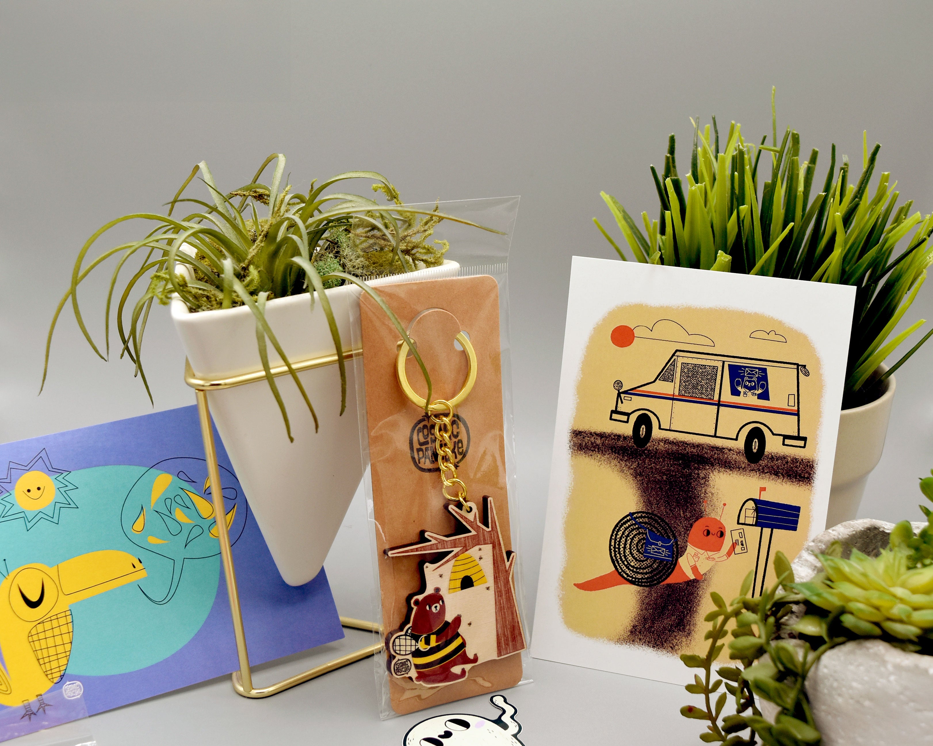 Decorative items including a plant, keychain, and postcard on a gray background