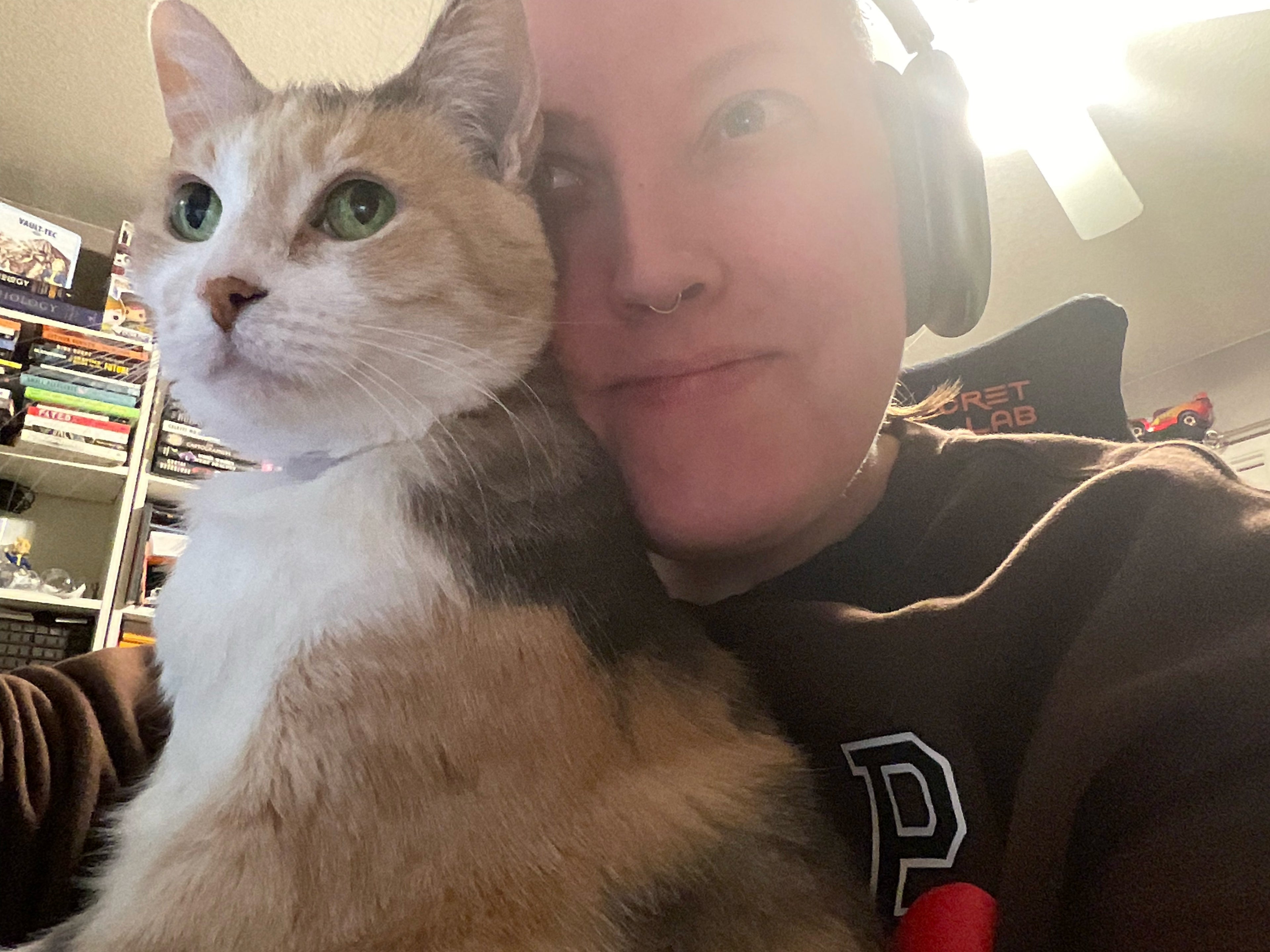 Person wearing headphones holding a cat indoors